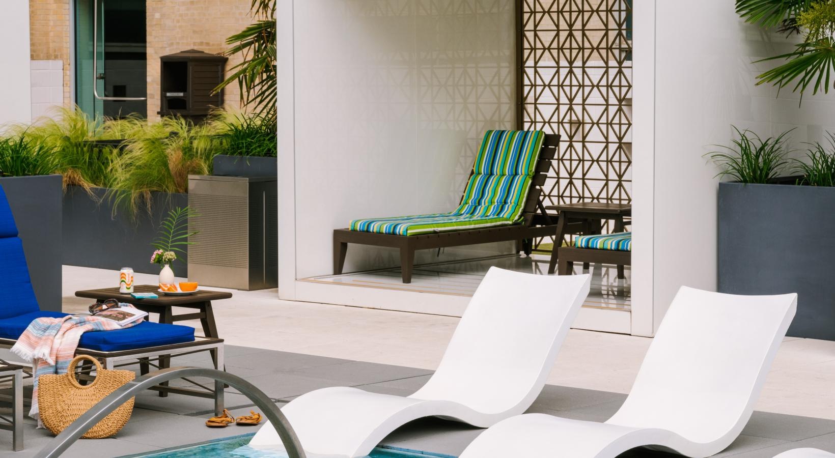 Settle into comfort at The Statler Residences a pool with chairs and a table